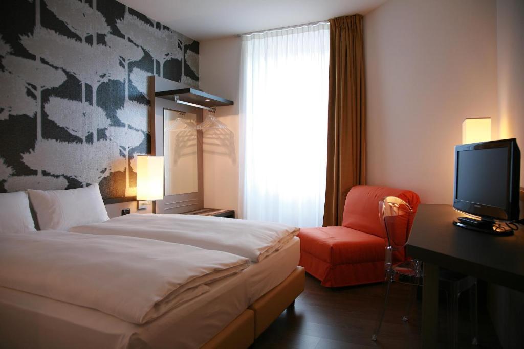 贝林佐拉Hotel Internazionale Bellinzona的一间卧室配有一张床、一台电视和一把椅子