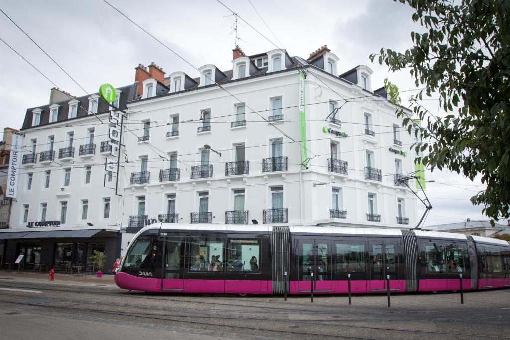 第戎第戎中心钟楼酒店 - 火车站的白色建筑前的粉红色电车