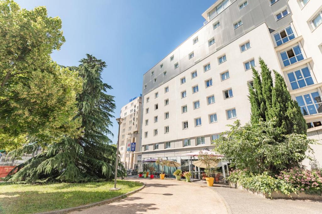卡威尔奎里昂康福特国际城市公寓式酒店的一座白色的大楼，前面有树