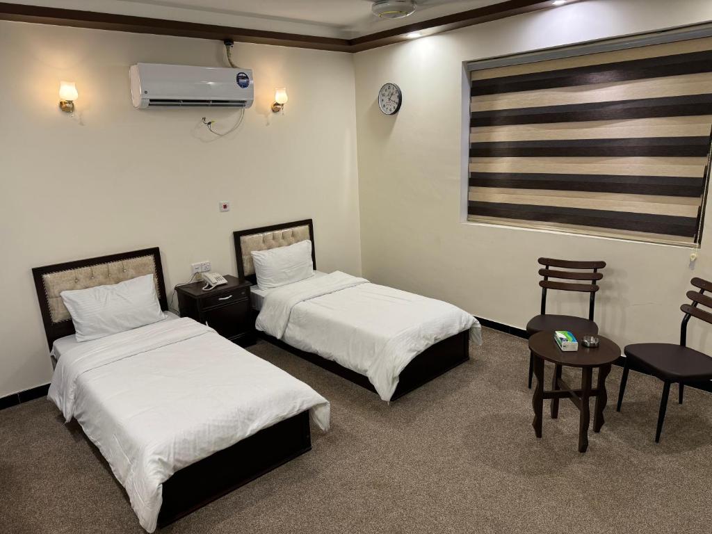 巴格达SAFIR BAGHDAD HoTEL的一间有两张床、一张桌子和几把椅子的酒店房间