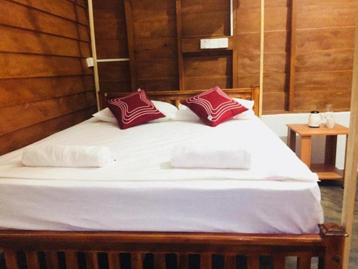 卢纳将军城Nena's Homestay的一张带白色床单和红色枕头的床