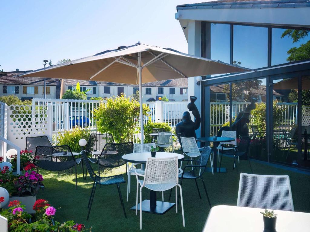 塞尔吉塞尔吉蓬图瓦兹乐港宜必思酒店的一个带桌椅和遮阳伞的庭院
