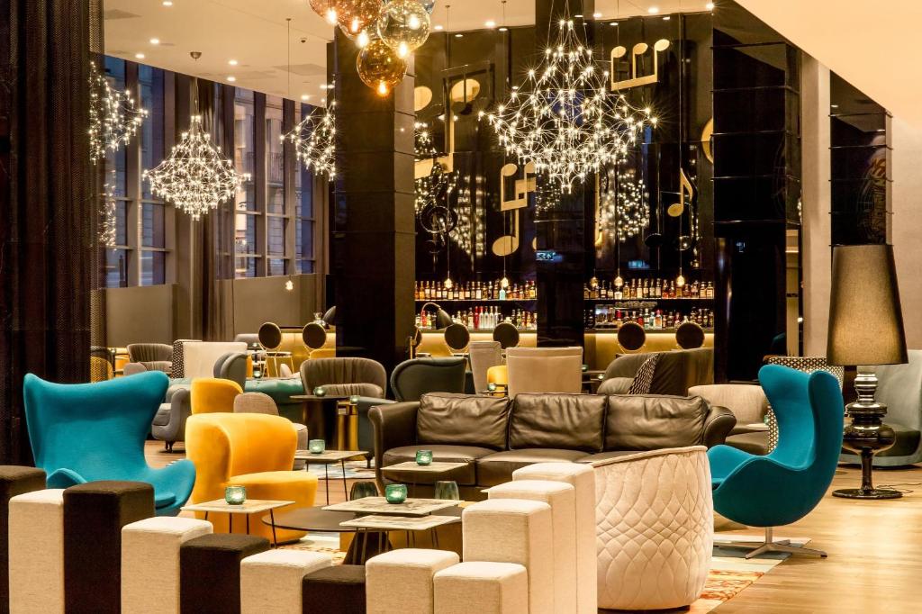 华沙Motel One Warsaw-Chopin的大堂配有沙发、桌子和吊灯。