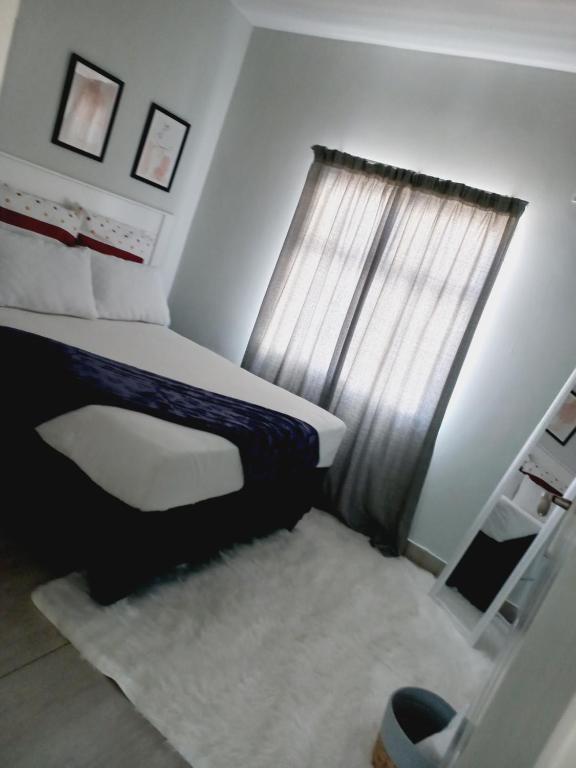 哈博罗内AGM Suites的一间卧室配有一张带窗户和地毯的床