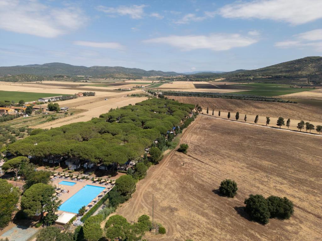 卡帕尔比奥Costa D'Argento - Camping Village Club Capalbio的享有带游泳池和田野的农场的空中景致