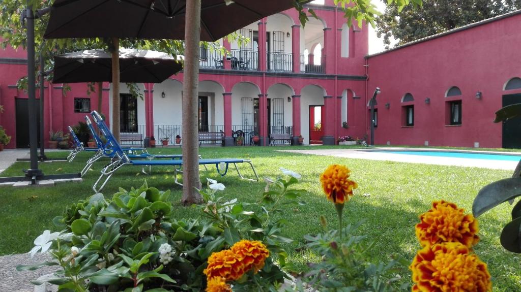 圣科洛马·德法尔噶拉尔特公寓酒店的一座粉红色的建筑,在院子里放着雨伞和鲜花