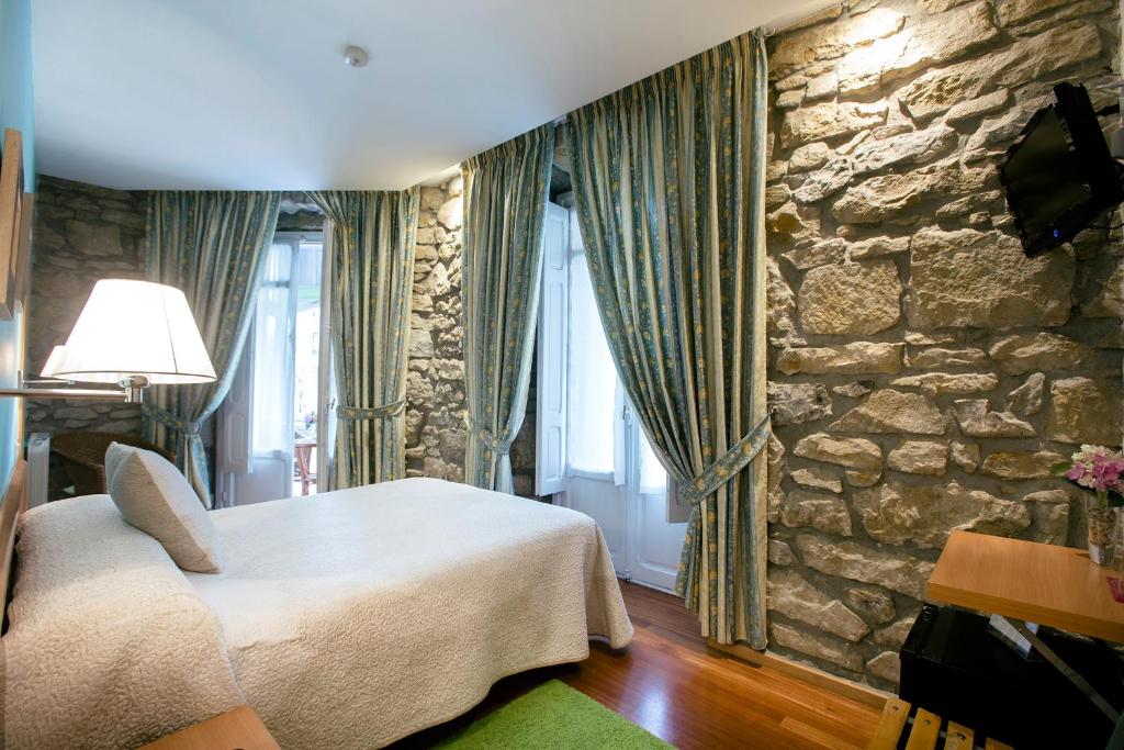 圣塞瓦斯蒂安新艺术膳食公寓的一间卧室设有一张床和石墙