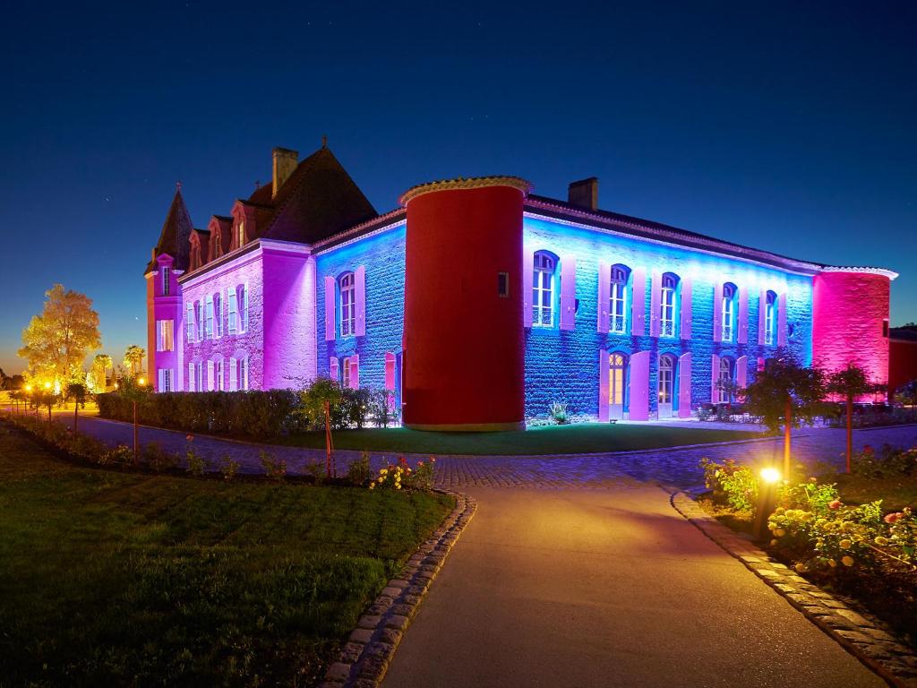 Saint-Sylvestre-sur-Lot斯特西亚酒店的一座建筑用蓝色和粉红色点亮
