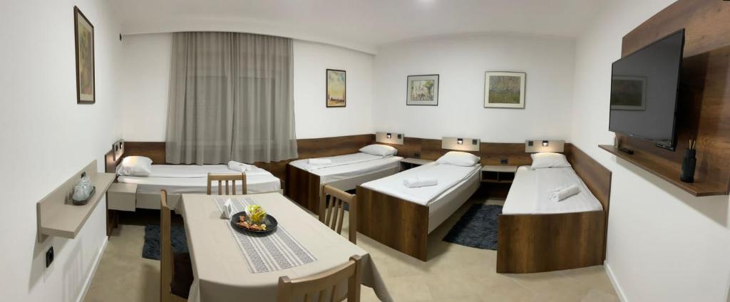 苏博蒂察Kollar D Guest House - Prenoćište ROOMS的客房设有三张床、一台电视和一张桌子