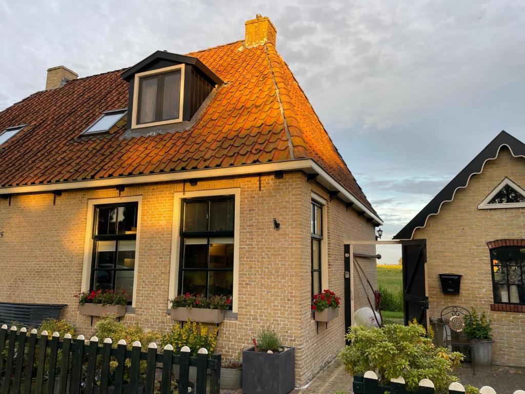 HunsVakantiehuis in Friesland voor de hele familie的一座砖房,有橙色屋顶