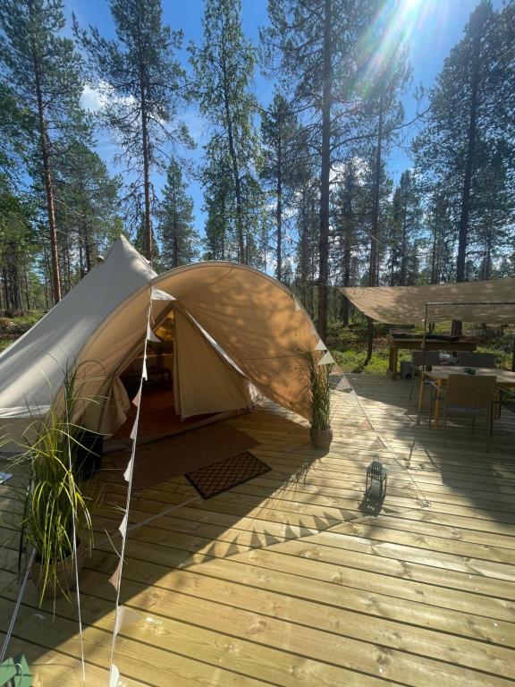 BjörklidenLaplandLiv Glampingtent with private sauna at the lake!的木甲板上的帐篷,配有野餐桌