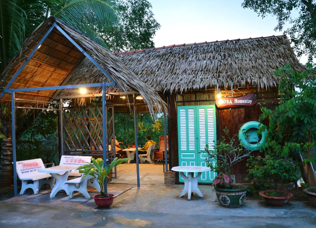 芹苴BOSA Homestay - Mekong Riverside的小屋前方设有桌椅的小小屋