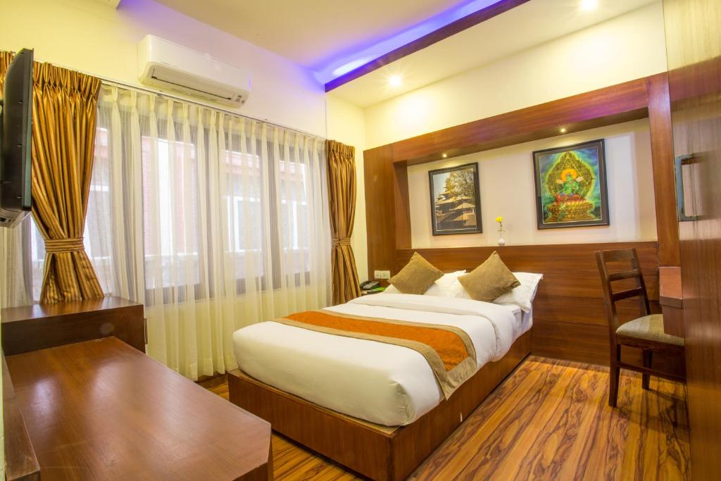 加德满都阿雅塔拉加德满都酒店的酒店客房设有一张大床和一张书桌。