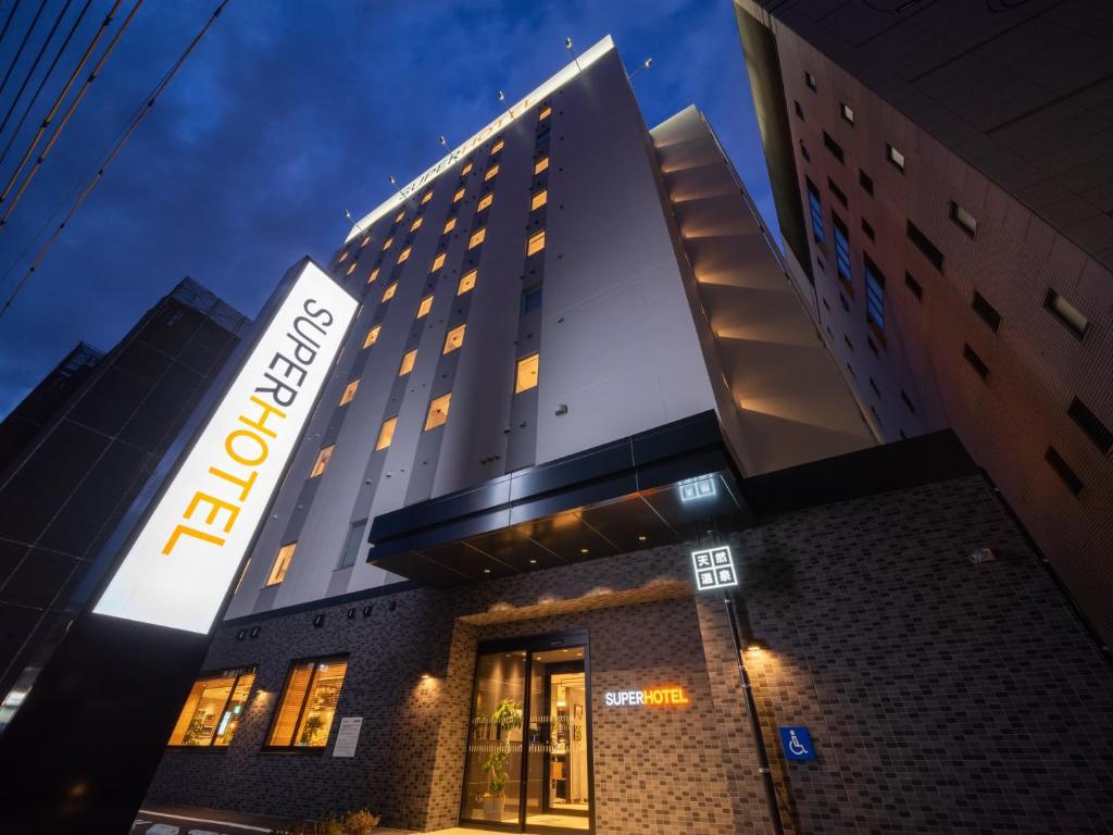 冈山Super Hotel Okayama Station Higashiguchi的建筑一侧有标志的酒店