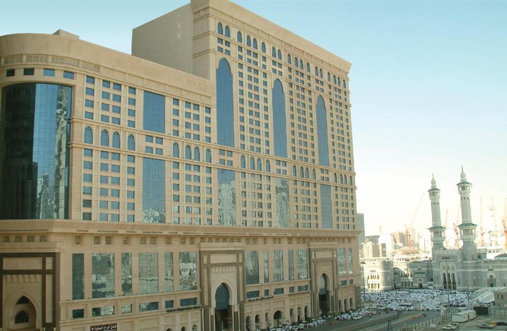 麦加Dorrar Al Eiman Royal Hotel的一座大型建筑,前面有汽车停放