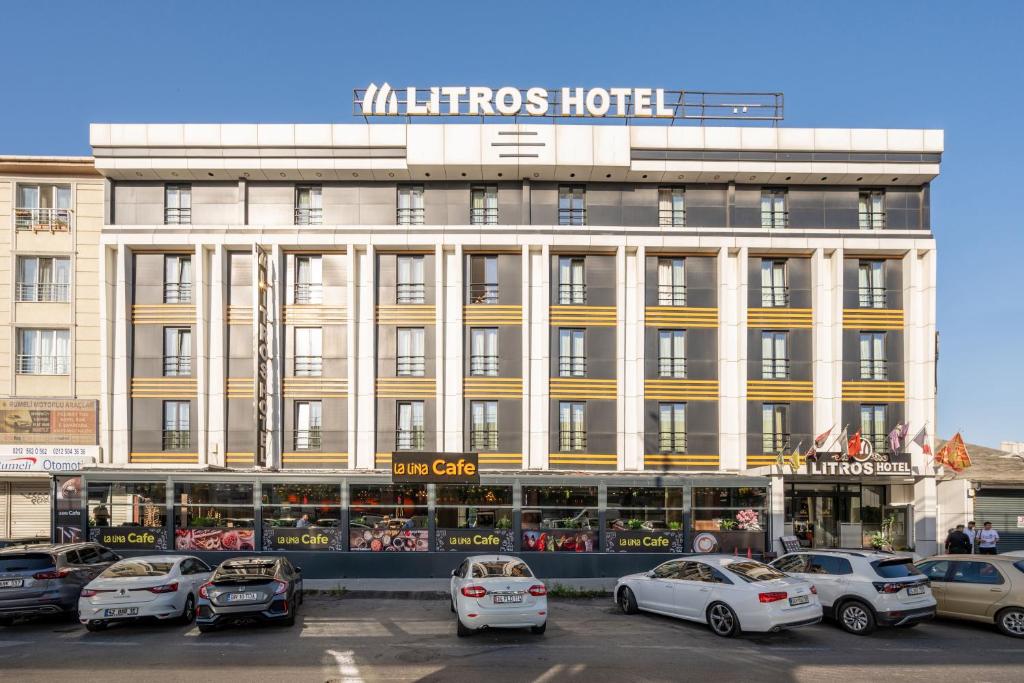 伊斯坦布尔Litros Hotel & Spa的一座大型建筑,前面有汽车停放