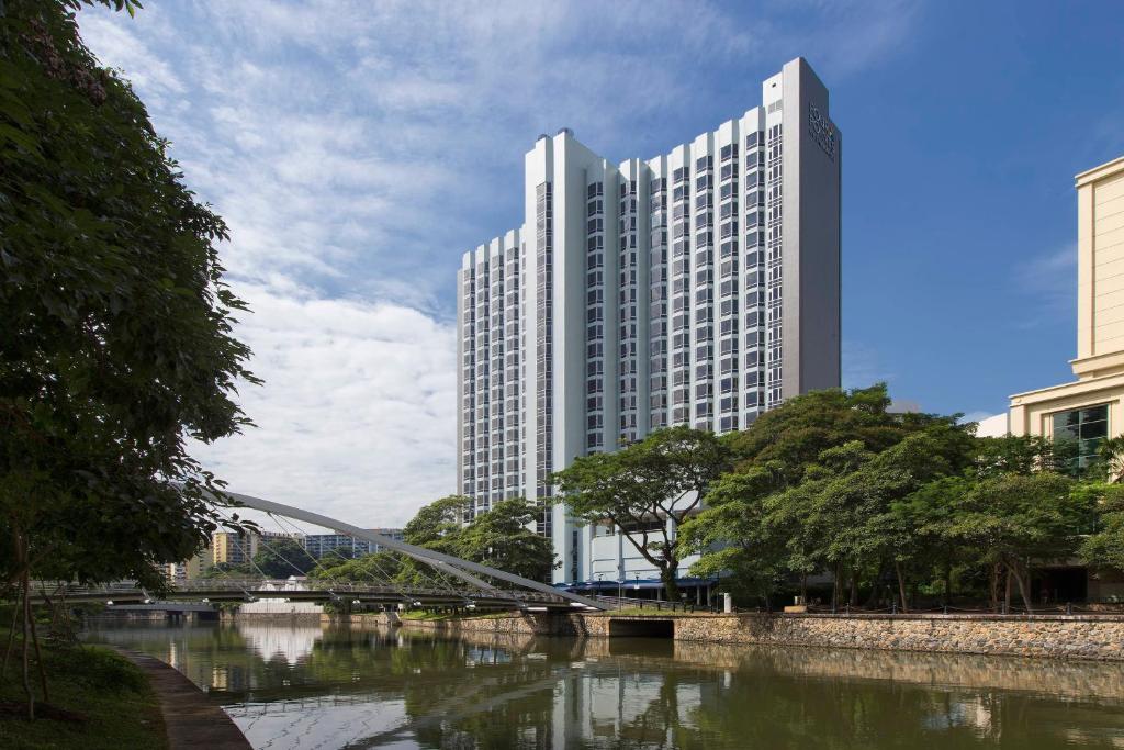 新加坡Four Points by Sheraton Singapore, Riverview的一座高大的建筑,靠近一条有桥的河流