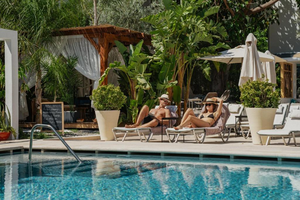 厄吕代尼兹Ölüdeniz Blu Luxury Unique Hotel - Adults-Only的两个女人坐在游泳池旁的椅子上