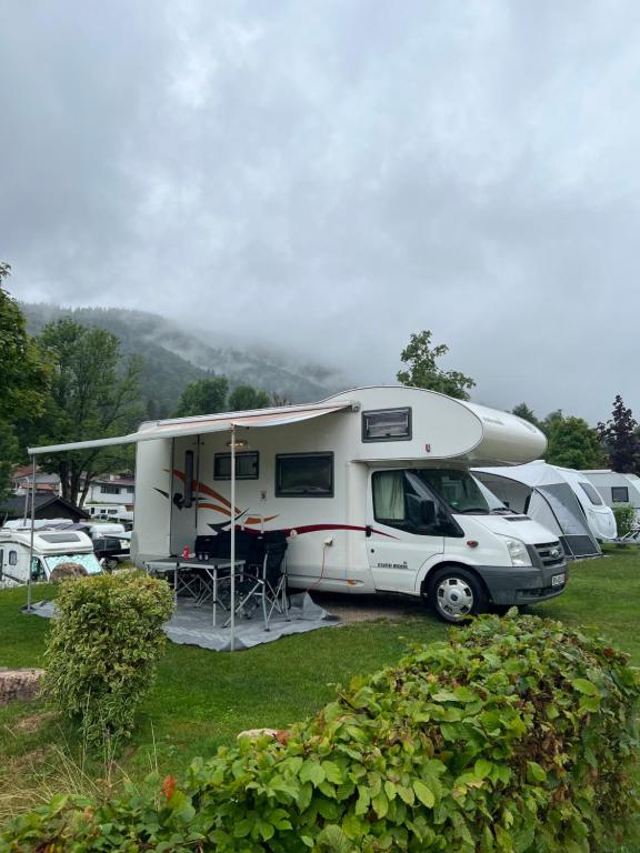 第比利斯Camper Mobile Motorhome的一辆白色大篷车停在带帐篷的停车场