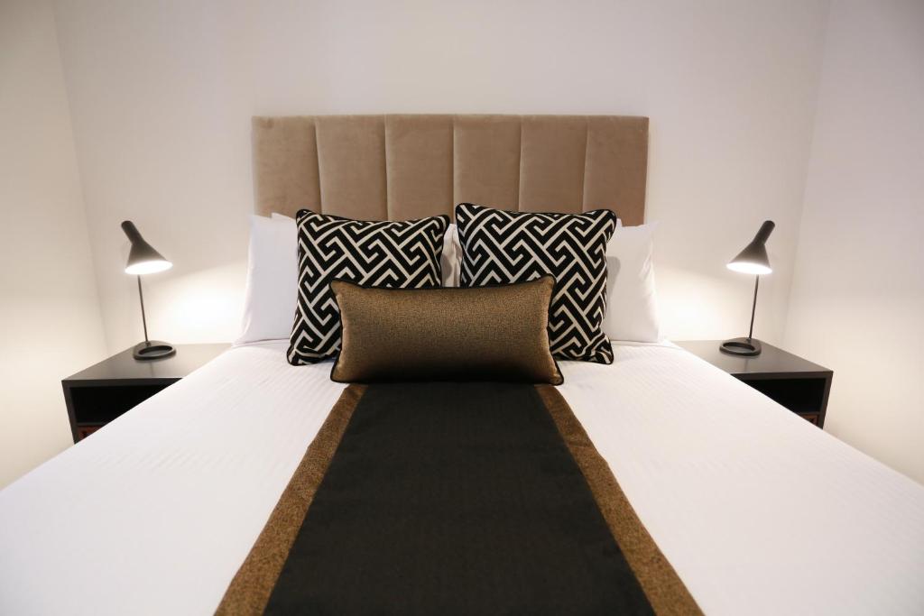 布里斯班亚历克斯佩里酒店及公寓的一间卧室配有一张带两盏灯的大型白色床。