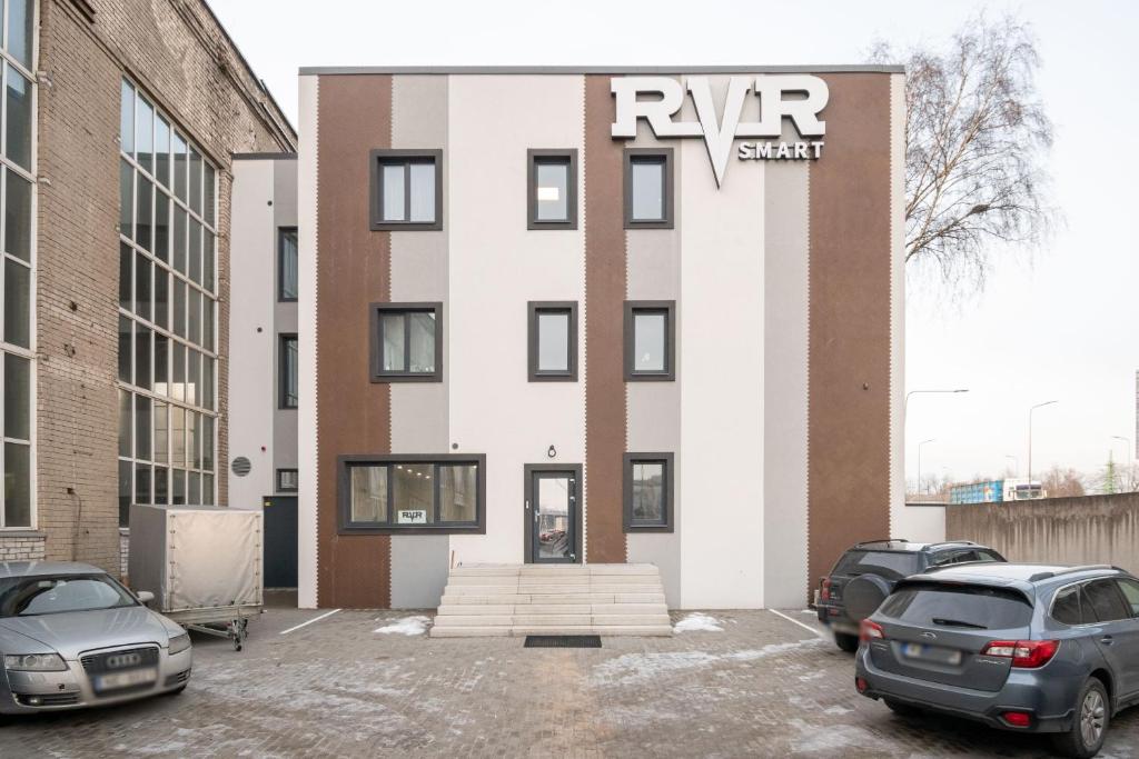 里加RVR Smart Apartments Riga with self Check-in的停车场内有车辆的建筑物