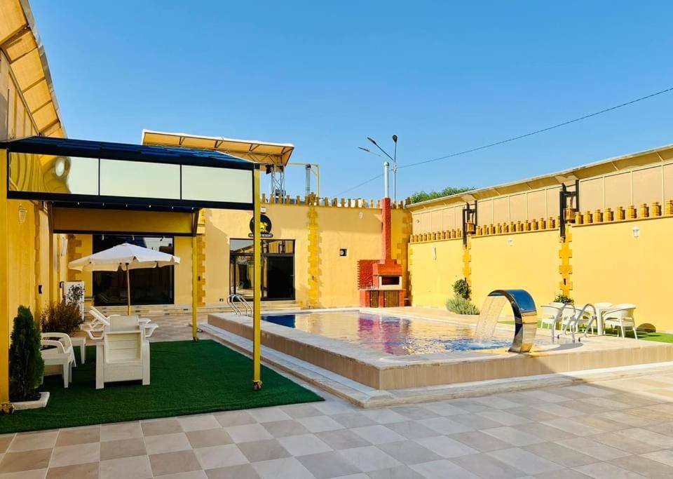 伊尔比德Kareem Resort منتجع كريم的黄色的建筑,设有配有桌椅的游泳池