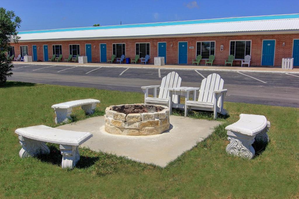 阿兰瑟斯港鲨鱼礁度假村汽车旅馆加小屋的停车场有三把白色椅子和一个火坑