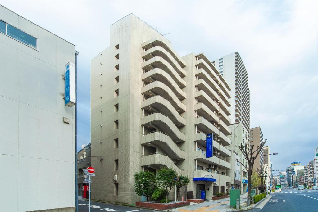 东京MYSTAYS 日暮里酒店的一条城市街道上高大的白色建筑