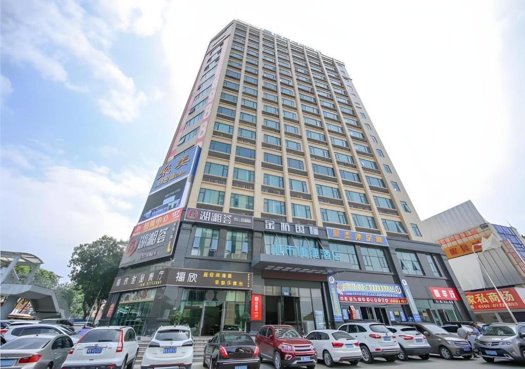 东莞City Comfort Inn Dongguan Tangxia Garden Street的停车场内有车辆停放的高楼