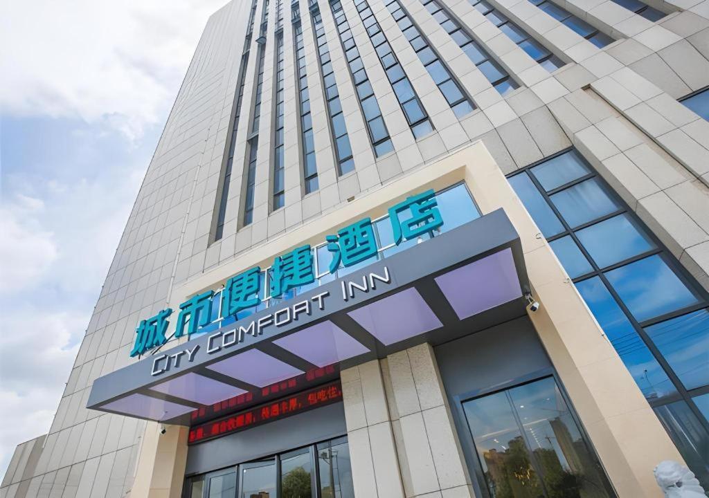 宣州区City Comfort Inn Xuancheng Wanda Qinglv Guoji的一座高大的建筑,前面有标志