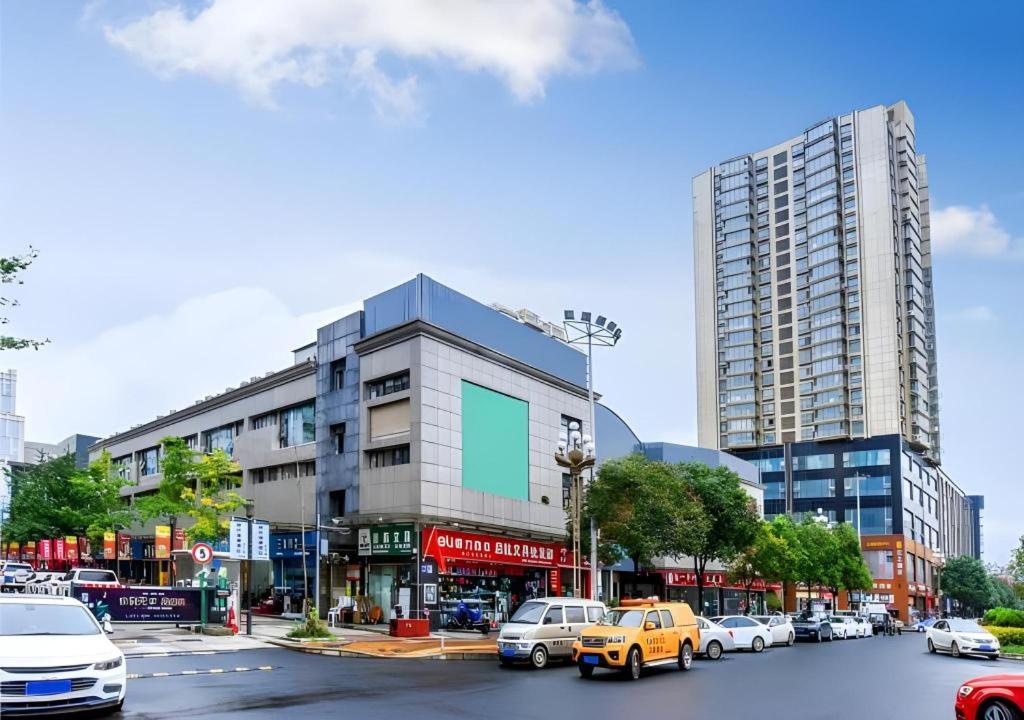 贵阳City Comfort Inn Guiyang Wanda Plaza Jiufu City的一条城市街道,汽车停在建筑前