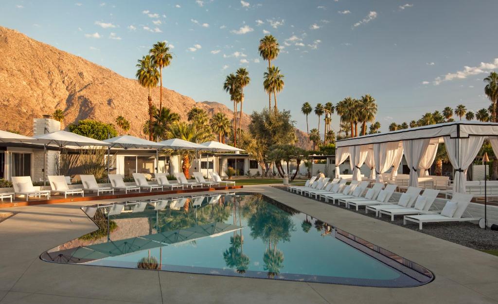 棕榈泉L'Horizon Resort & Spa, Hermann Bungalows的一个带白色椅子和棕榈树的度假游泳池