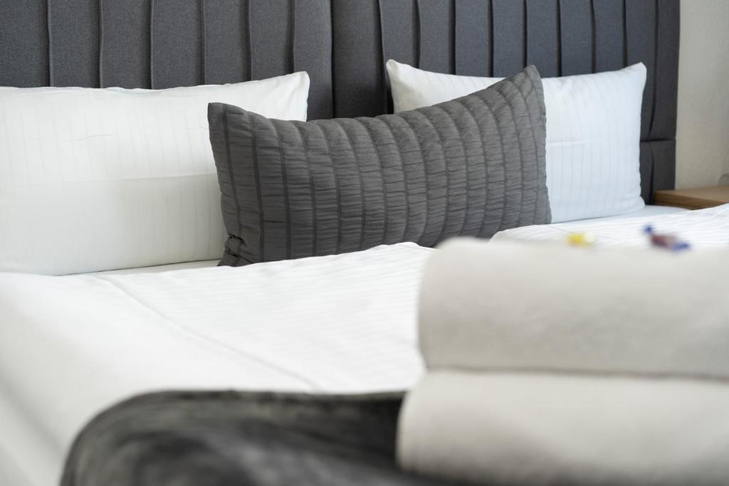 吕贝克Baltic Hotel Lübeck的一张带白色床单和灰色枕头的床