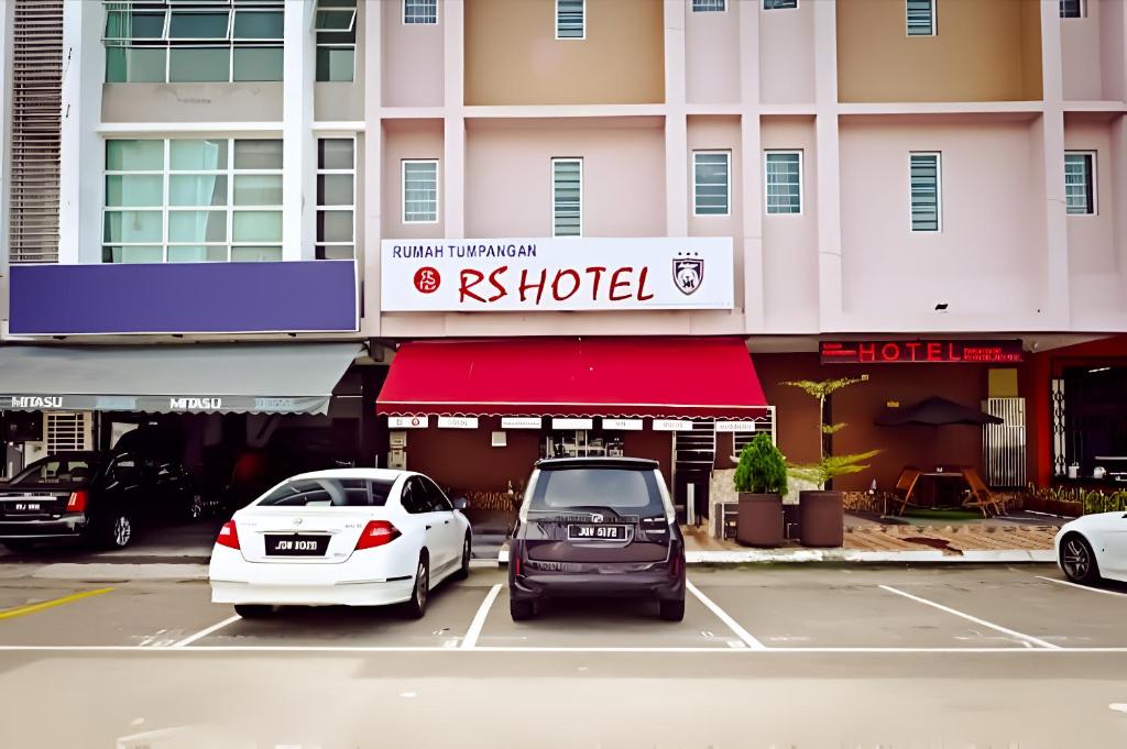 乌鲁地南Rs Hotel Johor的两辆汽车停在酒店门前的停车场