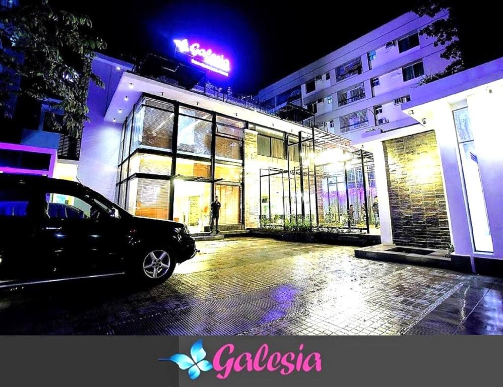 达卡Galesia Hotel & Resort的夜间停在大楼前的汽车