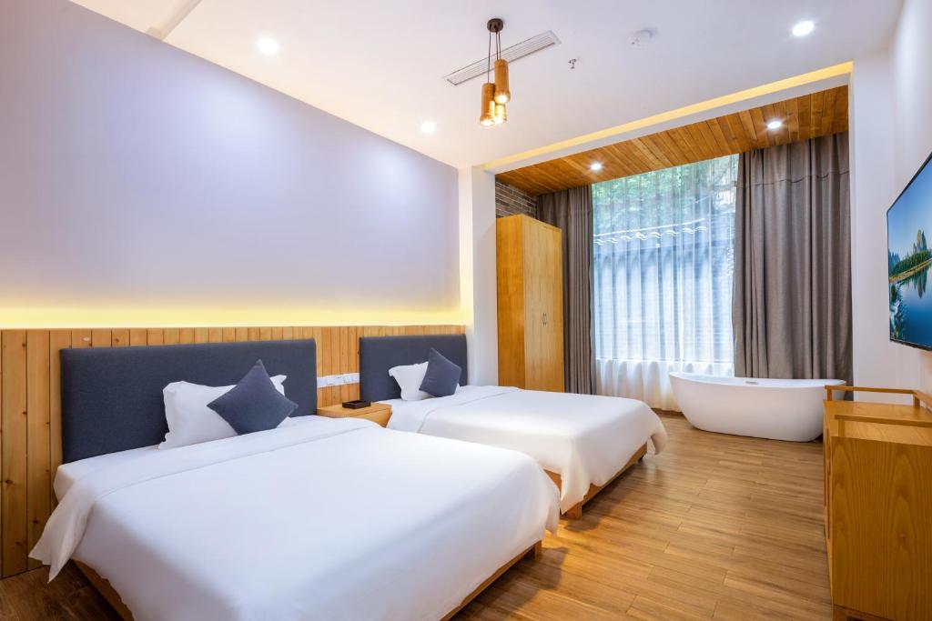 阳朔Qingshan Yuandai Resort Hotel Yangshuo Yulong River National Tourism Resort Store的带浴缸的酒店客房内的两张床