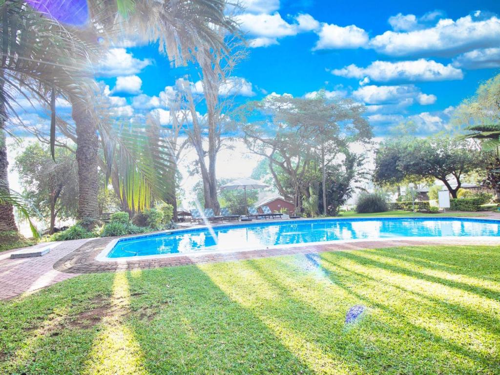 白河Hotel 247 @ White River的棕榈树庭院内的游泳池