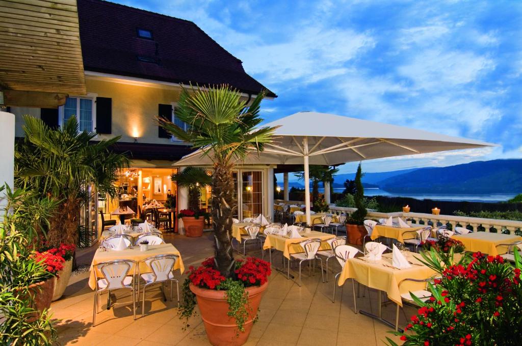 Mörigen塞布利克餐厅酒店的一间带桌椅和遮阳伞的餐厅