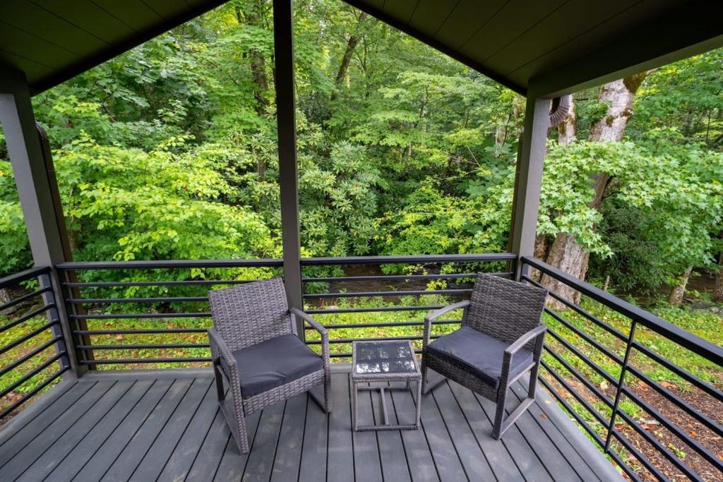 加特林堡Creekside Modern Tiny Home - Firepit - Racoon Cabin的门廊上的两把椅子和一张桌子