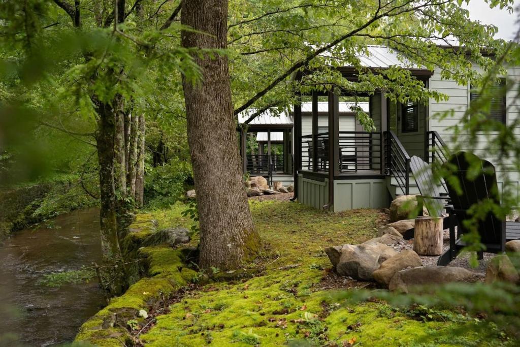 加特林堡Creekside Modern Tiny Home - Firepit - Racoon Cabin的带有前廊、树木和岩石的房子