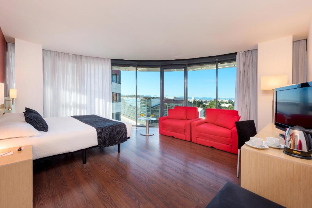 卡斯特利翁-德拉普拉纳Civis Luz Castellón 4*S的酒店客房,配有一张床和两张红色椅子