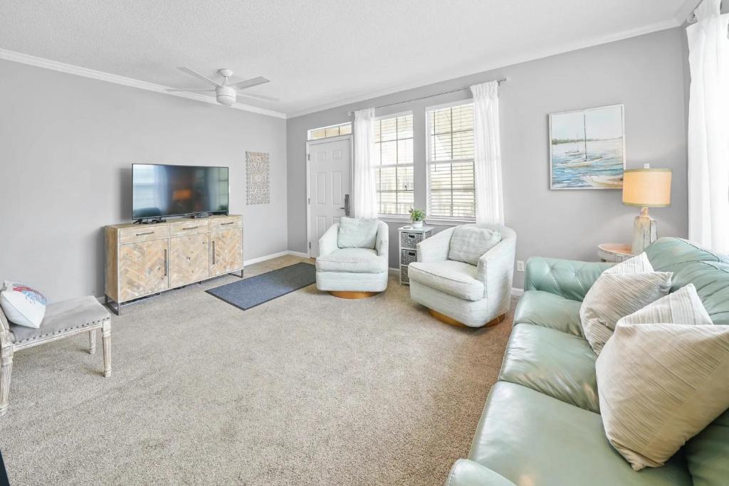 德斯坦Sunny escape in Miramar Beach的客厅里有一张沙发、两把椅子和一台电视