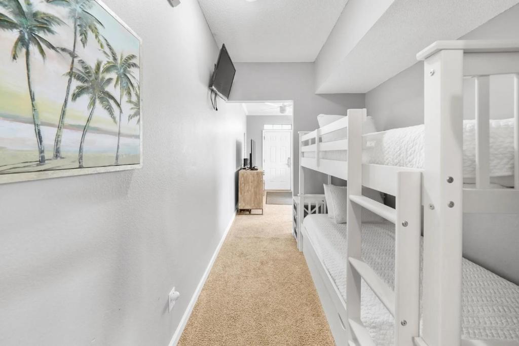 德斯坦Sunny escape in Miramar Beach的一间带双层床的卧室和一个带棕榈树的走廊