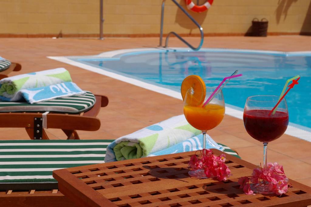 阿尔卡拉艾尔纳维奥乡村酒店-只接待成人的两杯酒坐在游泳池旁的桌子上