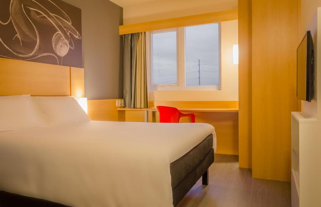 阿雷格里港Ibis Porto Alegre Assis Brasil的酒店客房设有床和窗户。