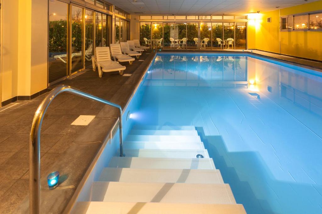 图卢兹Nemea Appart Hotel Toulouse Aéroport的一个带椅子和泳池景的大型游泳池