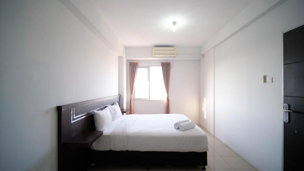 泗水Simple 2BR with Extra Bed at Menara Rungkut Apartment By Travelio的卧室配有白色的床和窗户。