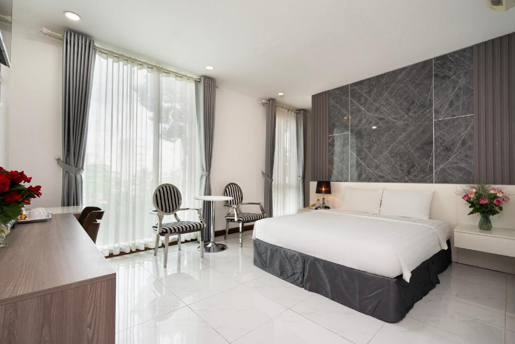 胡志明市Lam Kinh Hotel的卧室配有一张床和一张桌子及椅子