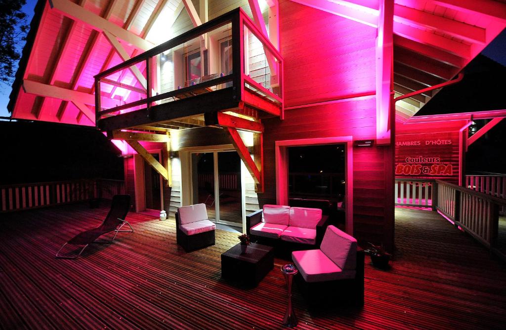 克松吕-隆日梅五色布瓦及水疗住宿加早餐酒店的甲板上设有粉红色照明的房屋