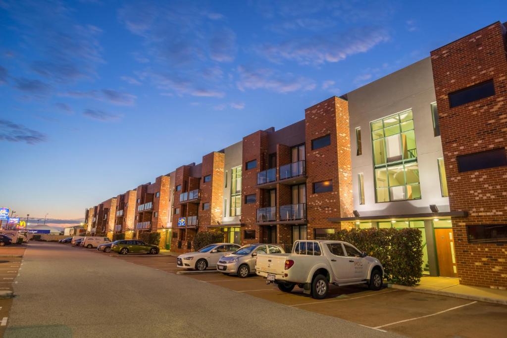 珀斯Perth Ascot Central Apartment Hotel Official的停车场内一排有汽车的建筑